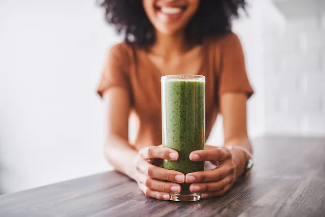 Woman drinking a green detox smoothie